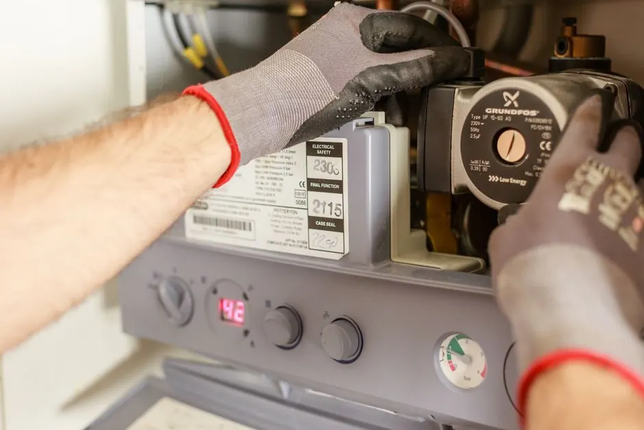 Hands adjusting boiler heating system components during a service inspection
